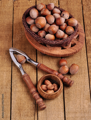 Hazelnuts in basket with walnut on wooden background