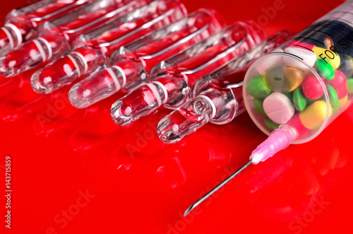 Syringe for subcutaneous injections with glass ampoules and multicolored tablets on an isolated background. Ampoule. Syringes