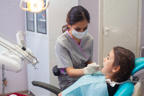pretty little girl opening his mouth wide during treating her teeth by the dentist