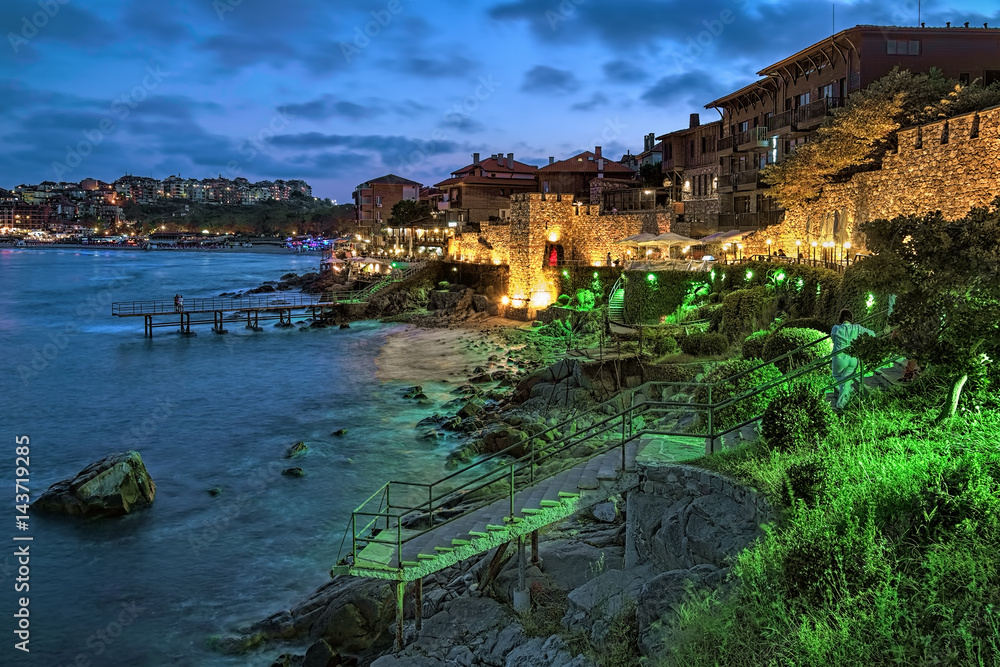 Southern Fortress Wall and Tower of the Old Town of Sozopol (former ancient town of Apollonia) with yellow-green illumination in twilight, Bulgaria. Sozopol is the famous resort on the Black Sea Coast