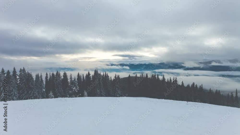 4k winter mountains with clouds and fog in sunset time. Ski slope, pine tree forest, mount range in the background. Majestic nature landscape. Holidays in Ski Resort Bukovel, Ukraine. Time lapse 4k winter mountains with clouds and fog in sunset time. Ski slope, pine tree forest, mount range in the background. Majestic nature landscape. Holidays in Ski Resort Bukovel, Ukraine. Time lapse