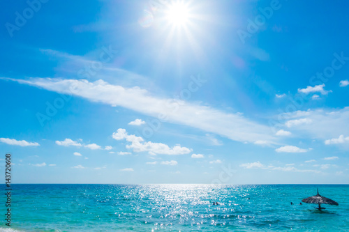 White clouds with blue sky and sun over calm sea in tropical Maldives island .