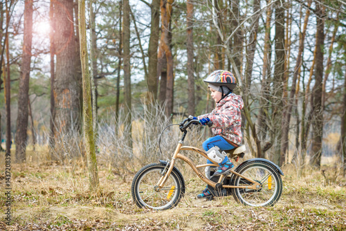 child on a bicycle in the forest in early morning. Boy cycling outdoors in helmet © pahis