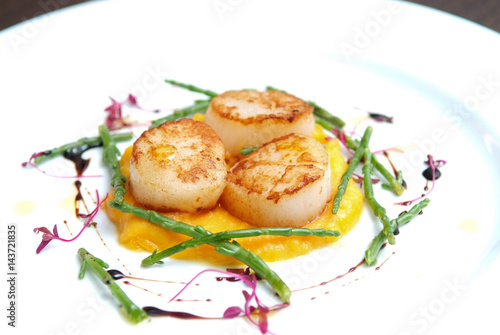 Scallops, creatively arranged food on a white restaurant plate