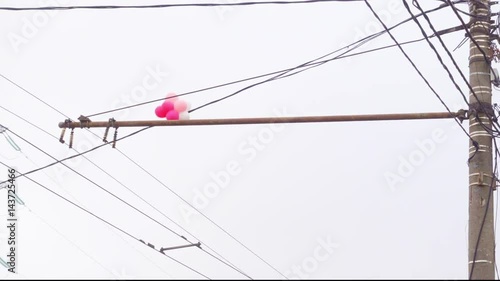 Balloons are stuck in electrical wires. Cloudy sky background