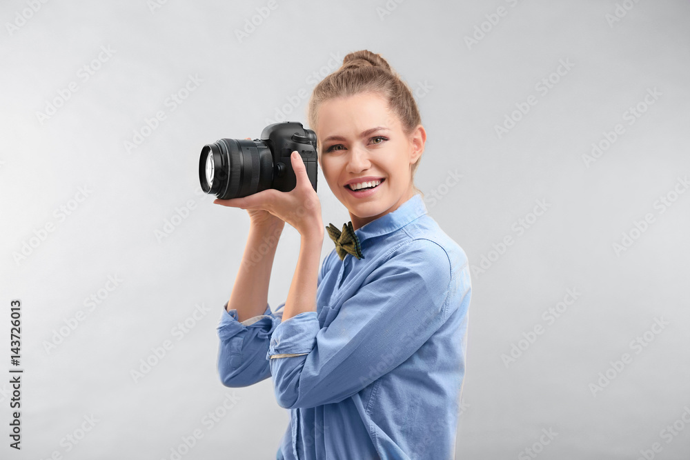 Beautiful female tourist with camera on light background Beautiful female tourist with camera on light background