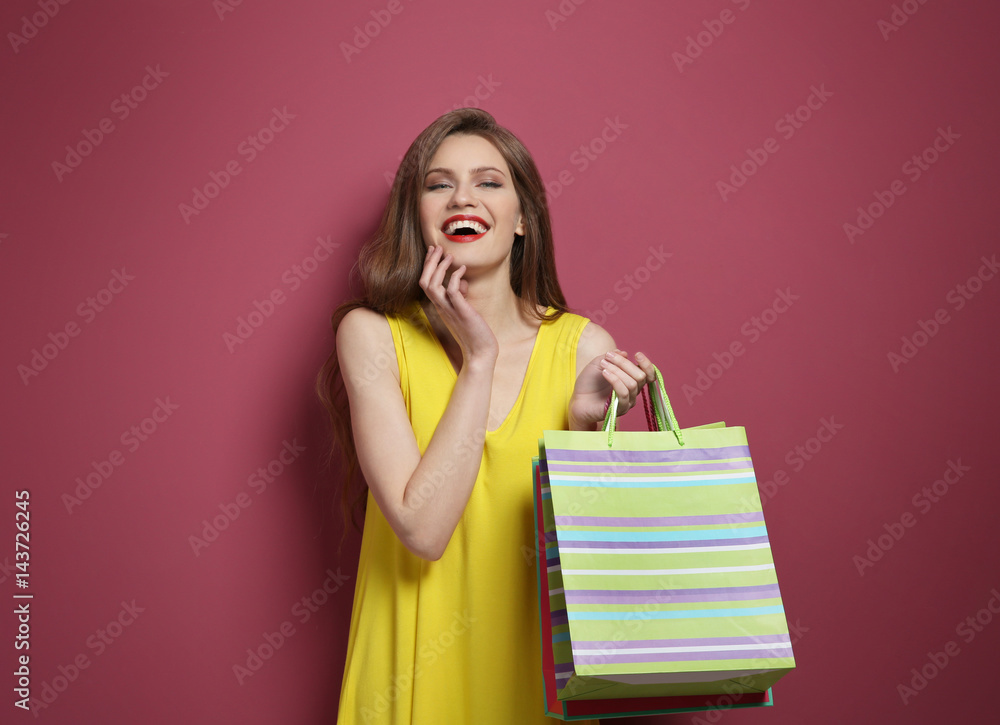 Beautiful young woman with paper bags on color background Beautiful young woman with paper bags on color background