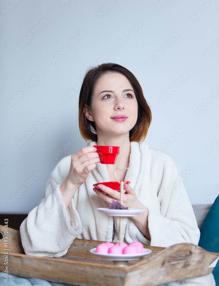 beautiful young woman holding her cup of coffee and sitting on the bed on wonderful bedroom background beautiful young woman holding her cup of coffee and sitting on the bed on wonderful bedroom background