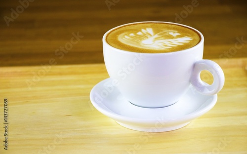 A cup of cappuccino is on wooden table