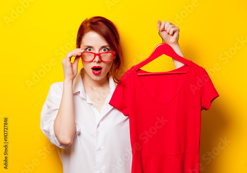 photo of beautiful young woman holding shirt on hanger on the wonderful yellow studio background