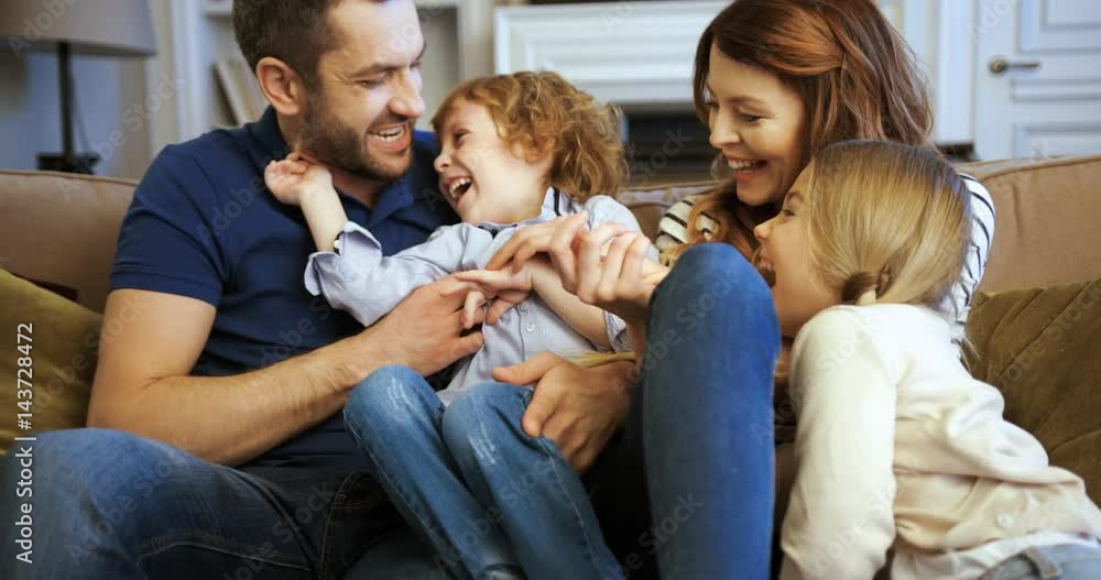 . Happy family spending time together at home. Happy young family sitting on the sofa Mother, father, son, daughter. Beautiful family laughing . Happy family spending time together at home. Happy young family sitting on the sofa Mother, father, son, daughter. Beautiful family laughing
