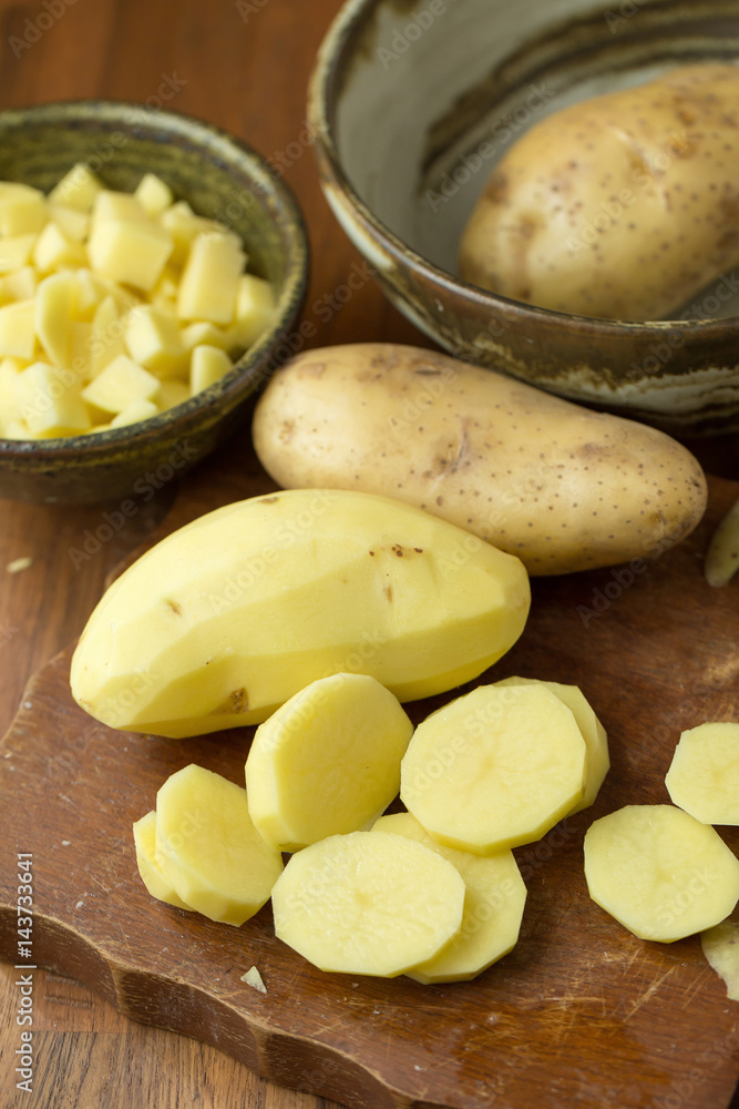 Potatoes and potato sliced on wooden table. Selective focus