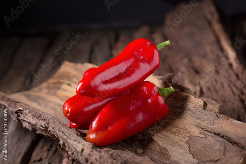 Red chilly pepper on wooden black background. Red hot chili peppers. photo