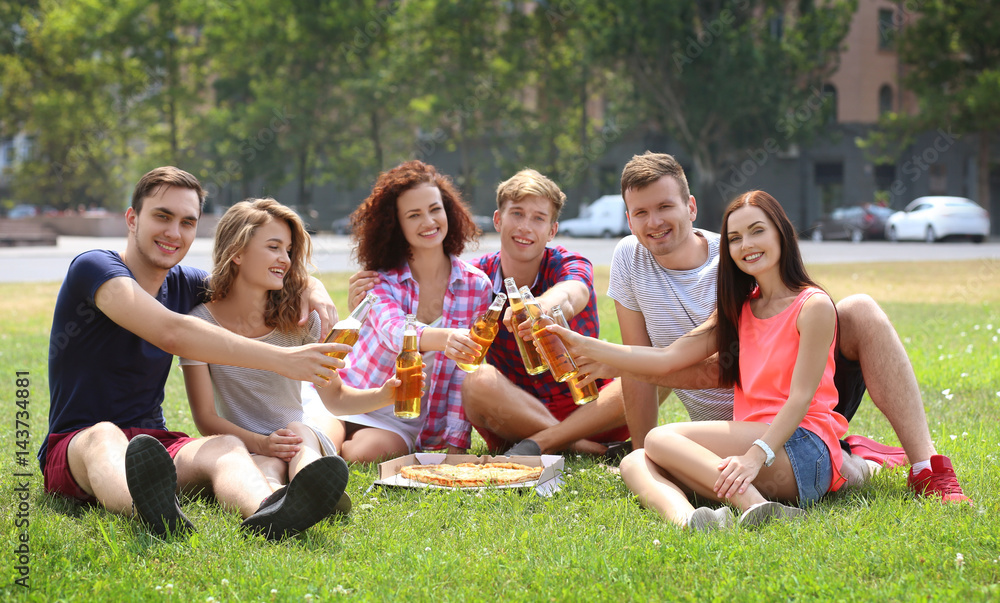 Young friends sitting on grass with pizza and beer Young friends sitting on grass with pizza and beer