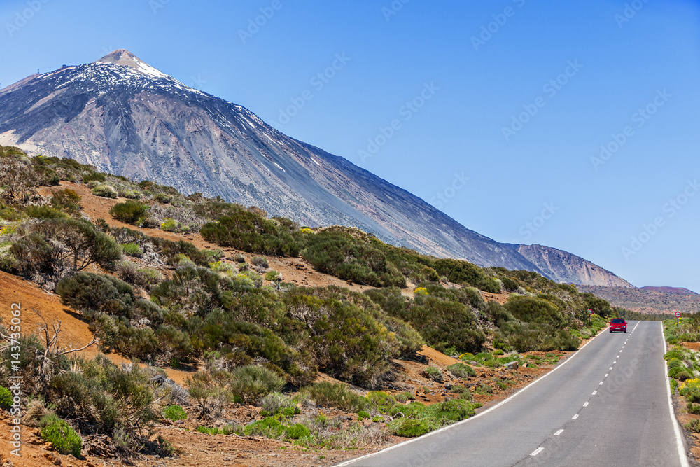 Red car driving on open highway near Teide volcano mountain summit, Tenerife, Canary islands. Freedom on holidays, road trip concept. Mountains in beautiful summer landscape. Red car driving on open highway near Teide volcano mountain summit, Tenerife, Canary islands. Freedom on holidays, road trip concept. Mountains in beautiful summer landscape.
