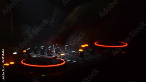 DJ Spinning, Mixing, and Scratching in a Night Club, Hands of dj tweak various track controls on dj's deck, strobe lights and fog, selective focus, close up. Dj Music club life concept