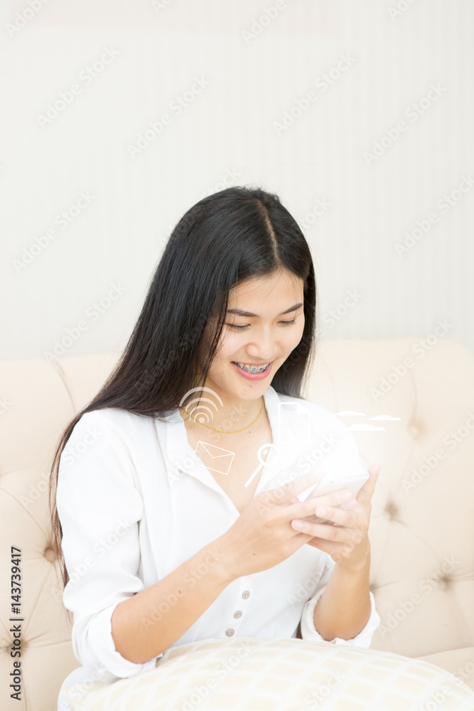 Pretty girl using her smartphone on couch at home in the living room Pretty girl using her smartphone on couch at home in the living room
