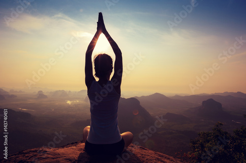 young fitness woman meditating on sunrise mountain peak