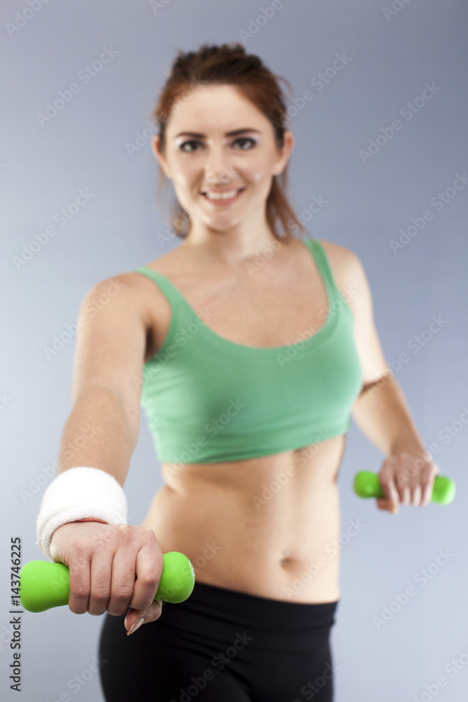 Green dumbbells in hands of fitness young woman. Blurred Figure Green dumbbells in hands of fitness young woman. Blurred Figure