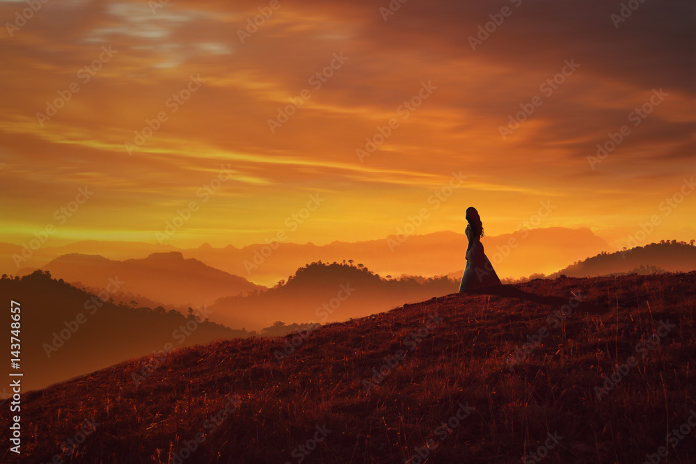 a lonely girl standing on cliff of a mountain