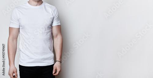 A portrait of a man having athletic body wearing blank white t-shirt standing on white background with copy space for your advertisment. Clothes advertising.T-shirt design and people concept.