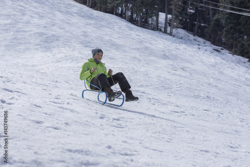 boy sledding in mountain warm winter day