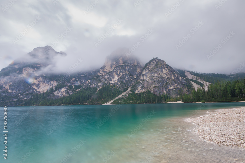 Fototapeta premium Cloudy and foggy morning on the alpine lake Lago di Braies, dolomites, italy