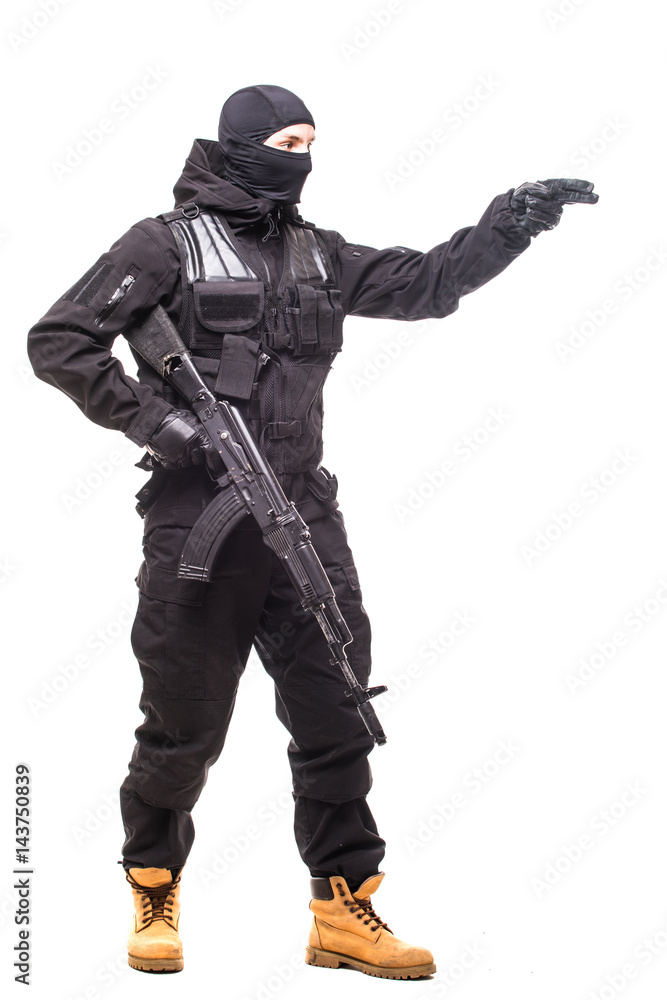 Portrait of dangerous bandit in black wearing balaclava and holding gun show sign in hand Portrait of dangerous bandit in black wearing balaclava and holding gun show sign in hand