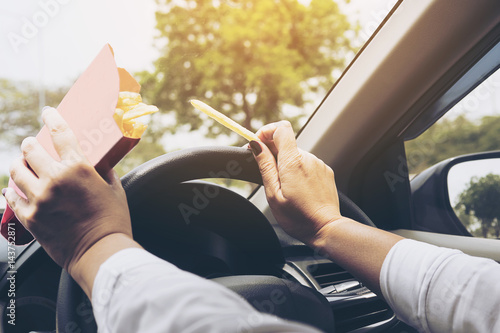 Lady eating french fries white driving car dangerously