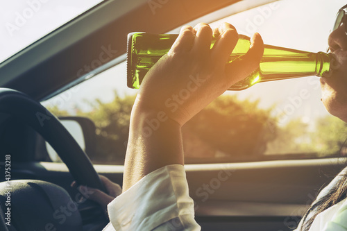 Woman drinking beer while driving a car