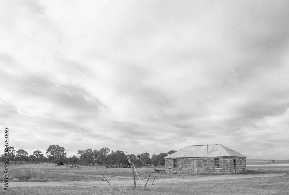 old bluestone building and storm clouds black and white