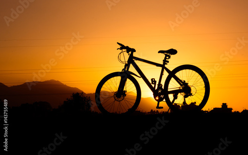 Fototapeta Naklejka Na Ścianę i Meble -  silhouette of parked bicycle on warm tone with some copy space