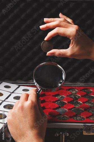 Hands with coin and magnifying glass, soft focus background