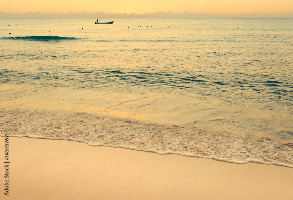 Colorful sunset on the tropical beach with beautiful sky, clouds, boat and soft waves. Photo from Playa Del Carmen, Riviera Maya, Mexico.