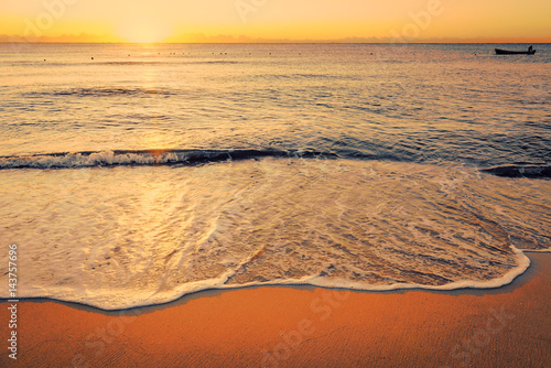 Colorful sunset on the tropical beach with beautiful sky, clouds, boat and soft waves. Photo from Playa Del Carmen, Riviera Maya, Mexico.