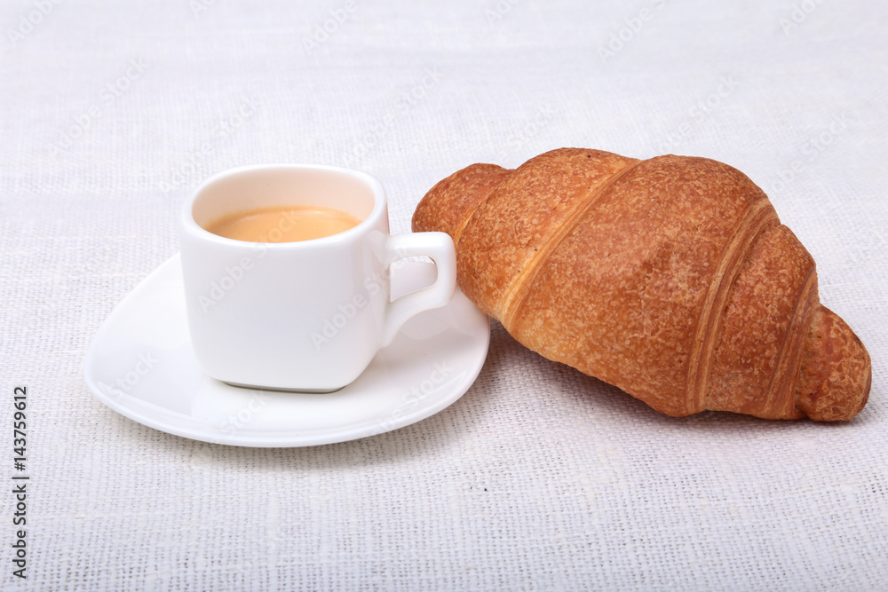 Crispy fresh croissants and cup of coffee espresso on a white background, morning breakfast, selective focus Crispy fresh croissants and cup of coffee espresso on a white background, morning breakfast, selective focus