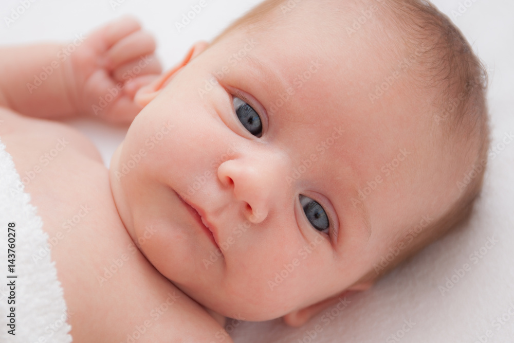 Cute adorable newborn baby girl in white bed and looking at the camera Cute adorable newborn baby girl in white bed and looking at the camera