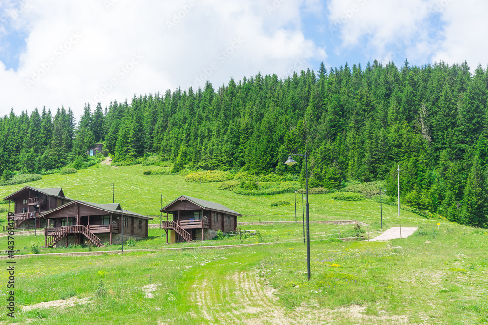 View of a wooden mountain cabin with mountains in the background View of a wooden mountain cabin with mountains in the background
