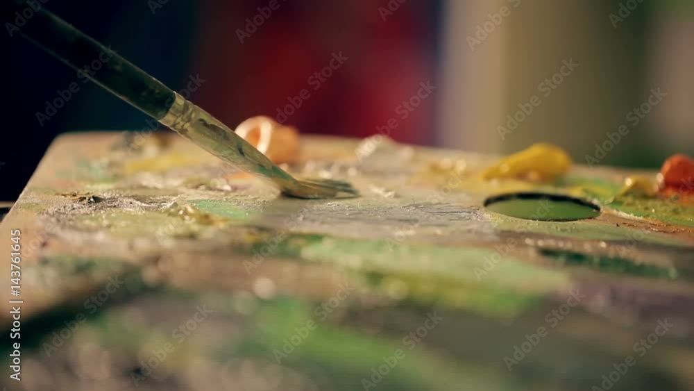 The artist mixes oil paint on a palette close up The artist mixes oil paint on a palette close up