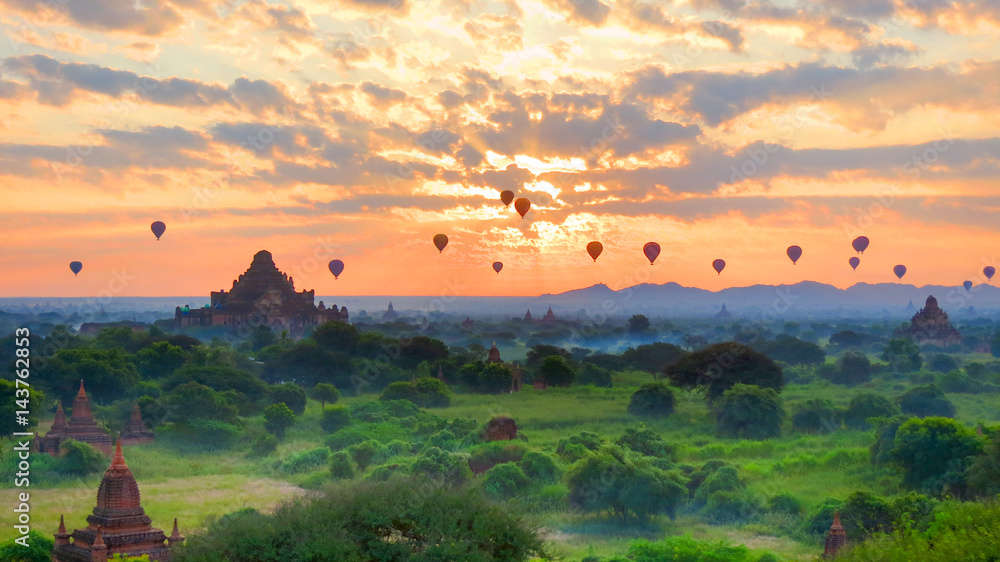 Bagan, Myanmar - sunrise over the many ancient pagodas with hot air balloons passing by