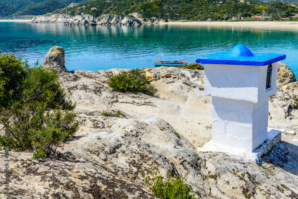 Small Greek white church or chapel with sea and mountain in background. Greek Orthodox shrine. Photo from Kalamitsi, Sitonia, Halkidiki, Macedonia, Northern Greece.