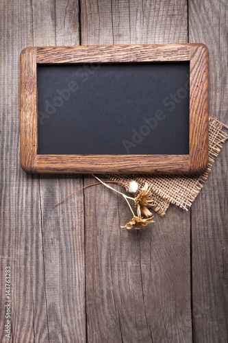 blackboard empty decorated with dried flowers on the old wooden table.