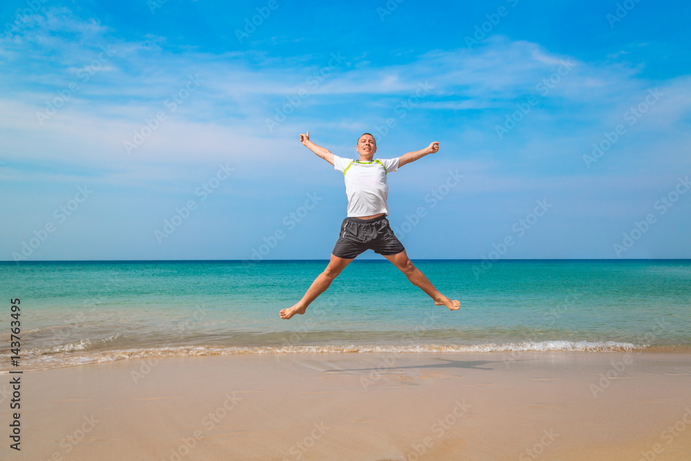 Happy tourist man jumping in a tropical beach
