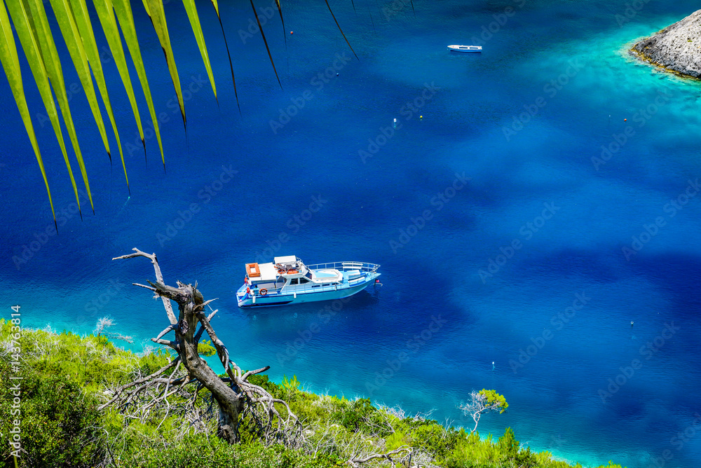 Boat, clear sea water and green palm leaves on tropical sea abstract background. Marine landscape.