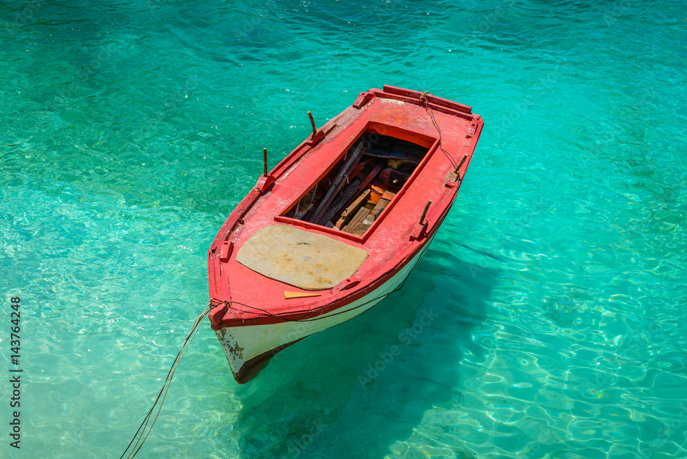 Background of seascape with small red fishing boat on clear water at Porto Vromi Bay, Zakynthos (Zante) Island, Greece. Marine landscape.