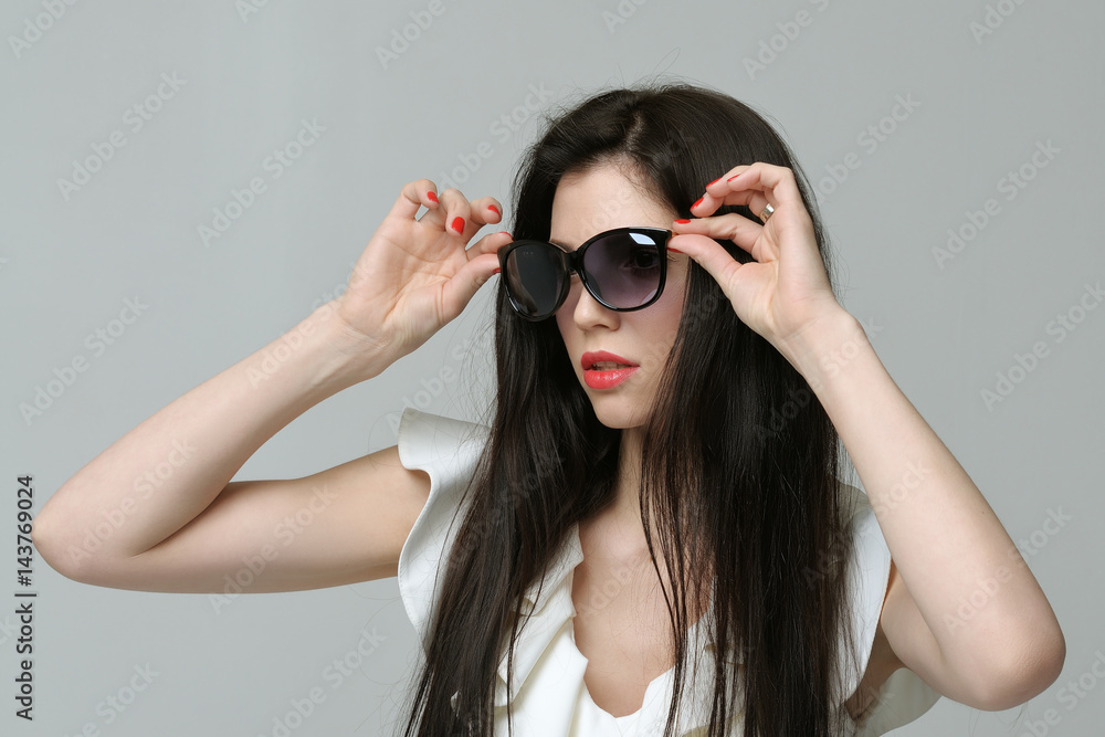 Portrait of a girl in a white dress who puts on sunglasses Portrait of a girl in a white dress who puts on sunglasses