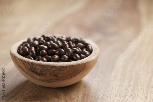 Quadro em tela small chocolate dragee in wood bowl on table, coffee beans or pine seeds