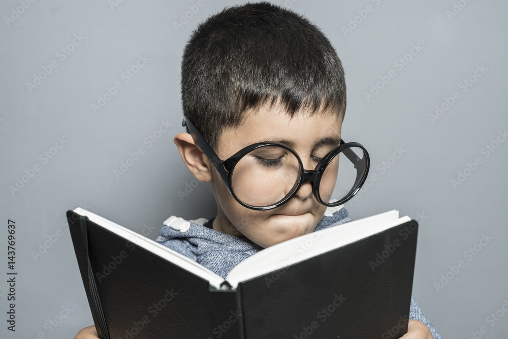 Boy with giant glasses reading a book with funny and varied gestures Boy with giant glasses reading a book with funny and varied gestures