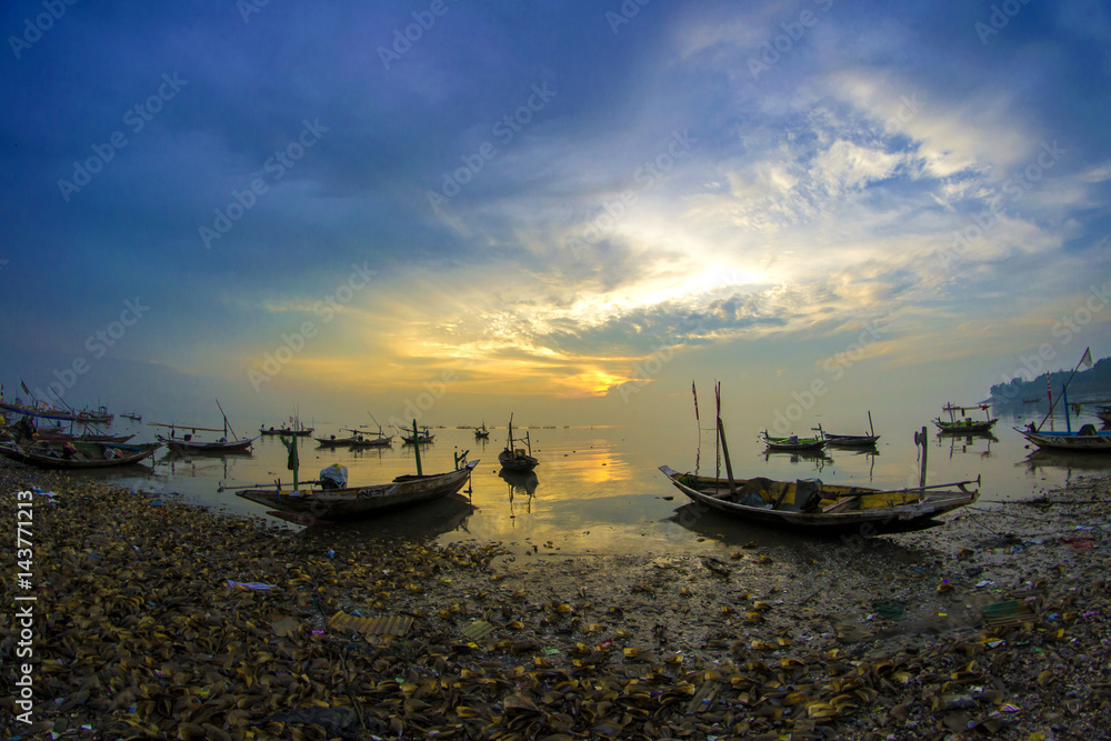 Silhouette of fishing boat on dock with sunrise in the background Silhouette of fishing boat on dock with sunrise in the background