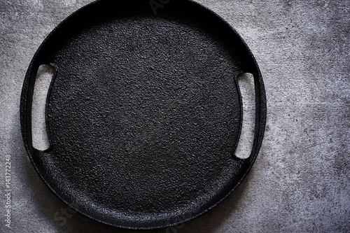 Empty rustic black cast iron plate On a concrete background. Top view with copy space